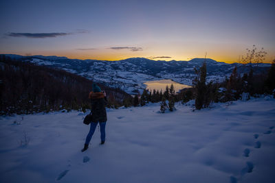 Man standing on snowcapped mountain against sky during sunset