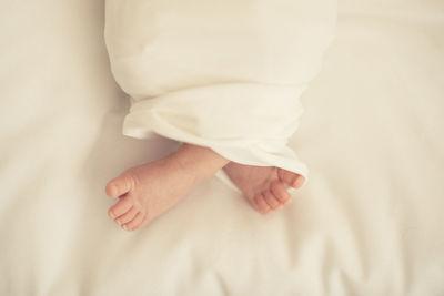 Low section of baby sleeping on bed