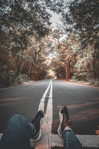 Low section of people walking on road in forest