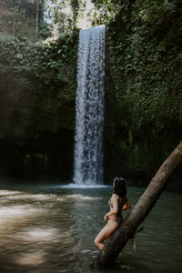 Rear view of woman sitting in water