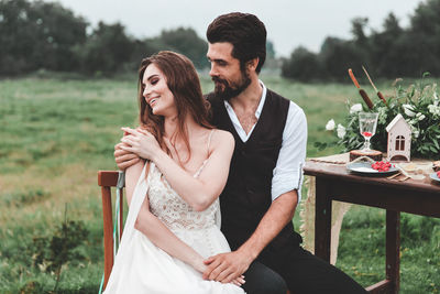 Happy wedding couple sitting on chair at farm