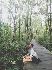 Man sitting on road amidst trees in forest