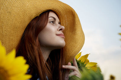 Portrait of young woman wearing hat against yellow background