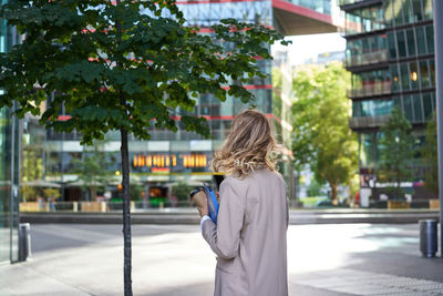 Side view of woman photographing while standing in city