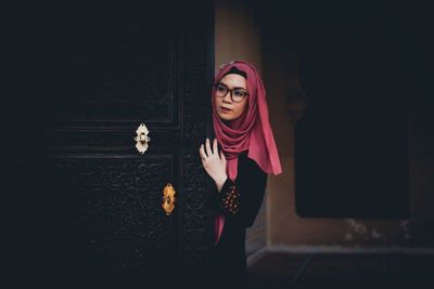 Woman in hijab standing by door