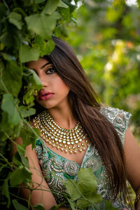 Portrait of young woman standing by plants