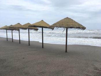 Deck chairs on beach against sky