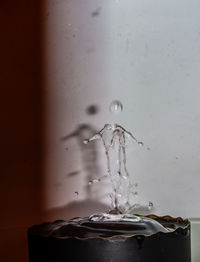 Close-up of water splashing on glass against wall