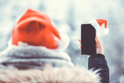 Midsection of person holding mobile phone during winter