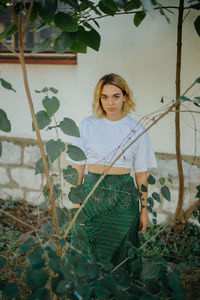 Young woman standing against plants