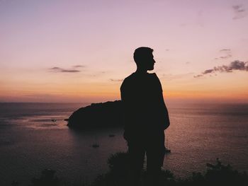 Silhouette man looking at sea against sky during sunset