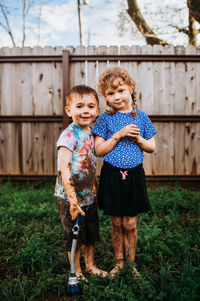 Two young kids playing in muddy backyard in spring