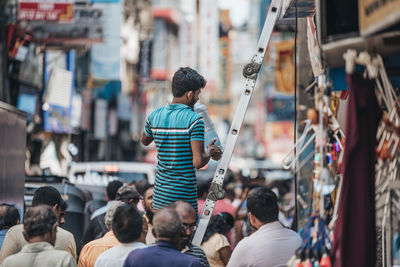 Rear view of people walking on street market in city