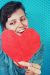 Smiling young woman holding heart shape paper
