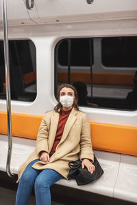 Portrait of woman wearing mask sitting in train