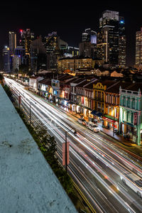 High angle view of light trails on street amidst buildings at night