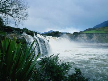 Scenic view of waterfall against sky