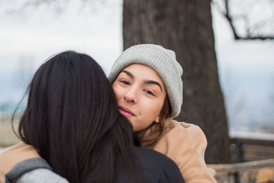 Close-up portrait of young woman embracing friends at outdoors