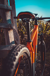 Portrait shot of the backside of an orange mountain bike against a corn field in autumn