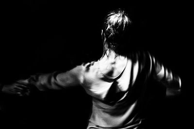 Rear view of woman standing against black background