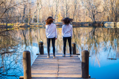 Rear view of women standing by lake