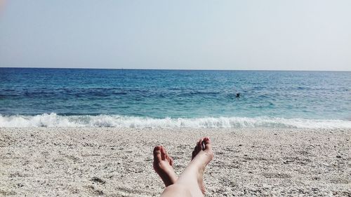 Low section of woman at beach against clear sky