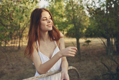 Smiling young woman against trees