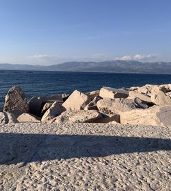 Scenic view of rocks on beach against sky, striking shadow 