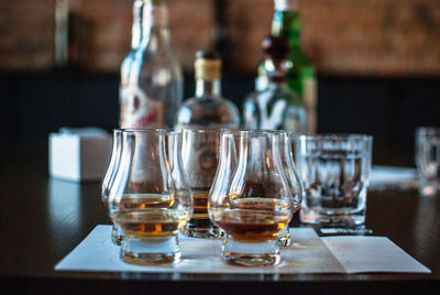 Close-up of whiskey glasses and bottles on table in bar