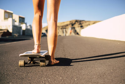 Low section of woman skateboarding on road