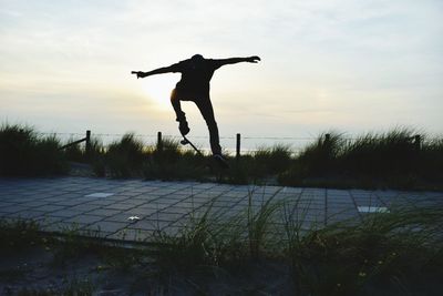 Silhouette man jumping in water at sunset