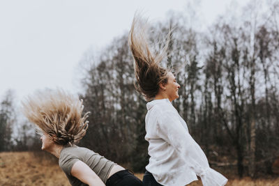 Rear view of friends against trees during winter