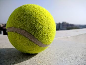 Close-up of tennis ball on retaining wall against sky