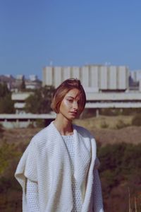 Portrait of young woman standing on field against clear sky