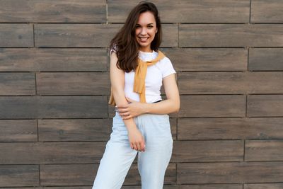 Portrait of young woman standing against wall