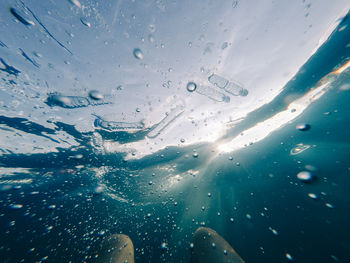 Close-up of wet glass against sea