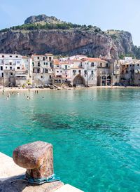 Sea by buildings against sky