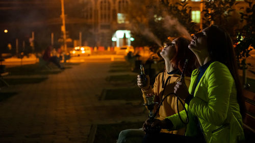 Women smoking hookah while sitting at park