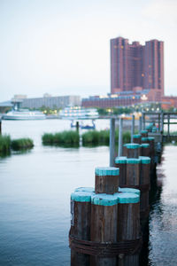 Wooden post on pier by river against sky in city