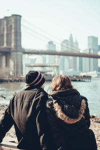 Rear view of couple kissing against river in city