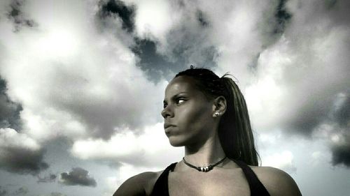 Portrait of young woman looking away against sky