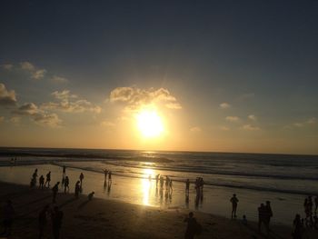 Silhouette people on beach against sky during sunset