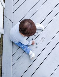 High angle view of boy sitting on wood