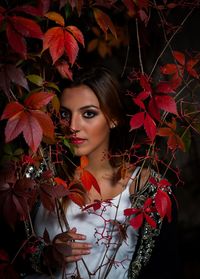 Portrait of young woman with red leaves during autumn