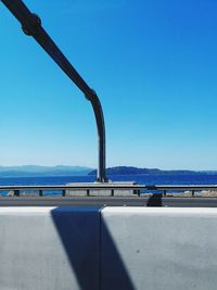 Road by sea against clear blue sky