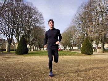 Full length portrait of man standing against bare trees