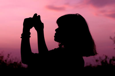 Silhouette woman standing against sky during sunset