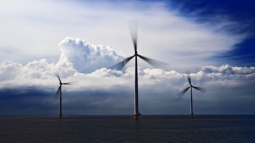 Wind turbines on field against sky