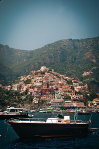 Sailboats moored on sea by city against sky