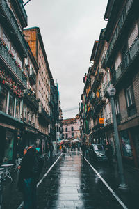 Wet street amidst buildings in city during rainy season